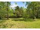Backyard showcasing a covered shelter among mature trees, creating a peaceful and shaded outdoor space at 209 Pen Lou Ct, Angier, NC 27501