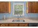 A well-lit kitchen sink beneath a window, complemented by wooden cabinets and modern appliances at 209 Pen Lou Ct, Angier, NC 27501