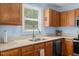 A kitchen sink with stainless steel faucet sits beneath a sunlit window and above wooden cabinets at 209 Pen Lou Ct, Angier, NC 27501