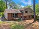 Side view of a two-story home featuring brick and siding with mature trees, set on a sloped lot at 2211 Hillock Dr, Raleigh, NC 27612