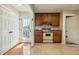 Kitchen featuring wood cabinets, linoleum flooring, and a door that leads to the backyard, offering natural light at 2211 Hillock Dr, Raleigh, NC 27612