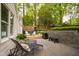 A backyard featuring a stone patio, wooden deck with seating, and lush green trees at 2415 Van Dyke Ave, Raleigh, NC 27607