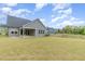 A spacious backyard with lush lawn, overlooking a pond, and a covered patio area at 2434 Heron Watch Pl, Fuquay Varina, NC 27526