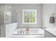 Beautiful bathroom with a luxurious tub, white marble tile, and natural light from the window at 261 Emory Bluffs Dr, Holly Springs, NC 27540