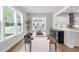 Elegant dining room featuring hardwood floors, large windows, a stylish table and chairs, and access to the kitchen at 261 Emory Bluffs Dr, Holly Springs, NC 27540