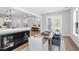 Dining area with hardwood floors, stylish table and chairs, and an open view to the kitchen and living room at 261 Emory Bluffs Dr, Holly Springs, NC 27540