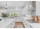 Bright, modern kitchen with white cabinets, quartz countertops, stainless steel appliances, and a large island at 261 Emory Bluffs Dr, Holly Springs, NC 27540