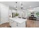 Open-concept kitchen with large island, stainless steel refrigerator, and hardwood floors extending to the living room at 261 Emory Bluffs Dr, Holly Springs, NC 27540