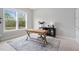 Bright home office with natural light, a modern desk, a chair, and a large window overlooking the yard at 261 Emory Bluffs Dr, Holly Springs, NC 27540