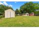 View of a large backyard featuring a storage shed, a small outbuilding, and a red barn at 2712 Cameron Dr, Sanford, NC 27332