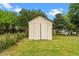 A weathered, white shed stands in a lush green backyard, offering ample outdoor storage space at 2712 Cameron Dr, Sanford, NC 27332