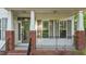 Charming front porch featuring brick accents, white pillars, black railing, and ample natural light at 286 Trillium Way, Clayton, NC 27527