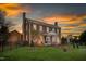 Stately brick home featuring a columned front porch and lush green lawn under a colorful sky at 3542 Bason Rd, Mebane, NC 27302