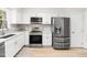 Updated kitchen featuring stainless steel appliances, white cabinets, and gray backsplash at 403 Mayodan Dr, Cary, NC 27511