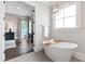 Bright bathroom with a freestanding tub, silver light fixture, and a view into a study area at 4237 Rowan St, Raleigh, NC 27609