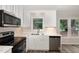 Close up of bright kitchen featuring white cabinets, stainless steel appliances, and large window at 5604 Groomsbridge Ct, Raleigh, NC 27612