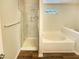 Modern bathroom with a glass-enclosed shower, soaking tub, and wood-look flooring at 5828 Brambleton Ave, Raleigh, NC 27610