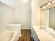 Bright bathroom featuring dual vanity sink, bathtub, wood floors, and ample counter space at 5828 Brambleton Ave, Raleigh, NC 27610