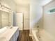 Well-lit bathroom featuring a double vanity, a soaking tub, and wood-look flooring at 5828 Brambleton Ave, Raleigh, NC 27610