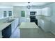 Well-lit kitchen with stainless steel sink, black appliances, island, and white cabinetry at 5828 Brambleton Ave, Raleigh, NC 27610
