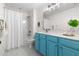 Bathroom with vibrant blue cabinets, shower and bath, large mirror, and ample lighting at 609 Conover Rd, Durham, NC 27703