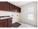 Laundry room with dark wood cabinets, tile flooring, and natural light from the window at 609 Conover Rd, Durham, NC 27703