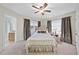 Primary bedroom with a ceiling fan, carpet, and beautiful upholstered bed with curtains and bright window light at 6212 Trevor Ct, Raleigh, NC 27613