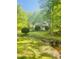 Backyard of a brick home showing a small stream, lush green grass and mature trees at 6212 Trevor Ct, Raleigh, NC 27613