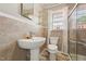 Updated bathroom with tiled walls, pedestal sink, glass enclosed shower, and natural lighting at 729 S Carolina Ave, Henderson, NC 27536
