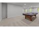 Wide view of basement with pool table, new carpet, natural light, and easy access to the backyard at 733 Holding Ridge Ct, Wake Forest, NC 27587