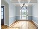 Stylish dining room with a coffered ceiling, hardwood floors, large windows, and updated modern lighting at 733 Holding Ridge Ct, Wake Forest, NC 27587