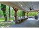Expansive covered deck with ceiling fan, built-in benches, and views of the lush, green backyard at 831 Healey Ln, Durham, NC 27705