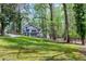 View of the house in the woods with a lush lawn and a driveway leading up to the home at 831 Healey Ln, Durham, NC 27705