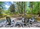Cozy fire pit area with gray Adirondack chairs nestled in a peaceful wooded setting at 831 Healey Ln, Durham, NC 27705