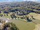Aerial view of the golf course, lake, and clubhouse nestled among the trees at 97302 Dobbs, Chapel Hill, NC 27517