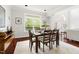 Well-lit dining room with hardwood floors, large window, a view of the outdoors, and ample seating at a wooden table at 97302 Dobbs, Chapel Hill, NC 27517