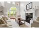 An airy living room with tall windows, a fireplace, hardwood floors, a white rug, and access to an outdoor deck at 97302 Dobbs, Chapel Hill, NC 27517