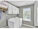 Well-lit laundry room featuring white appliances, cabinets, and a convenient folding rack at 1016 Leatherstone Ln, Fuquay Varina, NC 27526