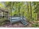 Side view of home with steps down from large deck surrounded by mature trees at 108 Maplewood Dr, Knightdale, NC 27545