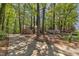 View of long, concrete driveway leading to traditional home surrounded by lush trees and vibrant azaleas at 108 Maplewood Dr, Knightdale, NC 27545