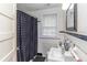 Classic white bathroom with black accents, a patterned shower curtain, and bright window at 1106 Sycamore St, Rocky Mount, NC 27801