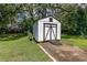 A white shed with black trim and a ramp in a landscaped backyard offers versatile storage options at 1106 Sycamore St, Rocky Mount, NC 27801