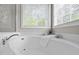 A close-up of a white garden tub and double windows with views of the outdoors at 112 Natchez Ct, Cary, NC 27519