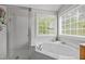 Bright bathroom featuring a garden tub, glass enclosed shower, and double windows at 112 Natchez Ct, Cary, NC 27519