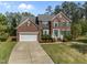 Stately brick home with a well-manicured lawn, attached two car garage, and charming green shutters at 112 Natchez Ct, Cary, NC 27519