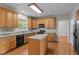 Well-lit kitchen with wood cabinets, black appliances, and a center island at 112 Natchez Ct, Cary, NC 27519