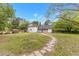Lush backyard featuring a stone walkway, mature trees, and a charming country home at 119 Johnson St, Broadway, NC 27505