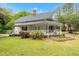 Charming two-story white home with a welcoming wraparound porch, vibrant landscaping, and an American flag at 119 Johnson St, Broadway, NC 27505