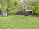 Spacious backyard featuring a storage shed and a house with a wooden deck, surrounded by lush trees at 1204 Hydrangea Ct, Hillsborough, NC 27278