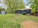 Home exterior with well-maintained yard, storage shed, and wooden deck, enveloped by mature trees at 1204 Hydrangea Ct, Hillsborough, NC 27278